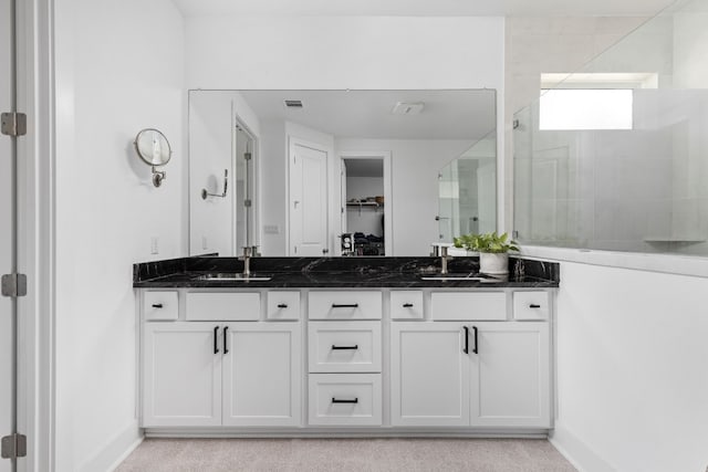 full bath featuring a tile shower, a spacious closet, visible vents, a sink, and baseboards