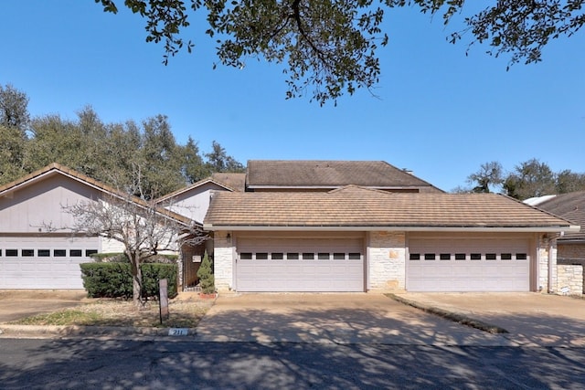 11512 Tin Cup Dr Unit 211, Austin, TX 78750 - view of front of home featuring concrete driveway, stone siding, an attached garage, and a tiled roof