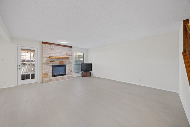 11512 Tin Cup Dr Unit 211, Austin, TX 78750 - unfurnished living room featuring wood finished floors, healthy amount of natural light, a textured ceiling, and a stone fireplace
