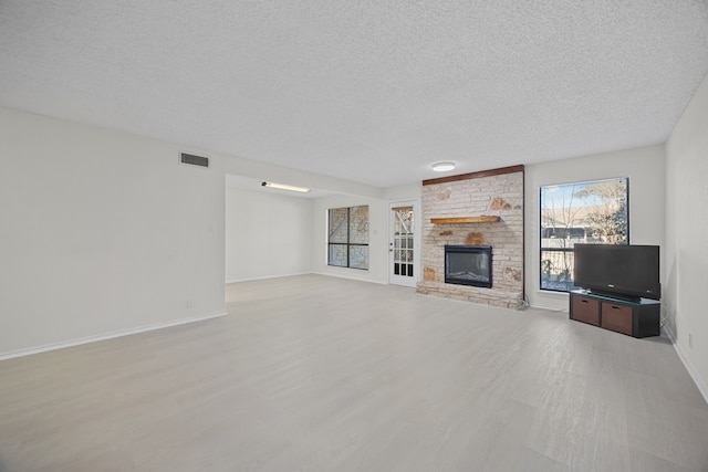 11512 Tin Cup Dr Unit 211, Austin, TX 78750 - unfurnished living room with wood finished floors, a textured ceiling, and a fireplace