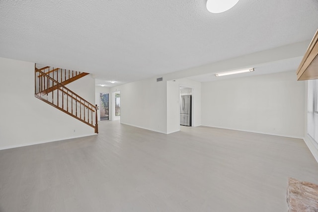 11512 Tin Cup Dr Unit 211, Austin, TX 78750 - below grade area featuring freestanding refrigerator, light wood finished floors, stairway, baseboards, and a textured ceiling