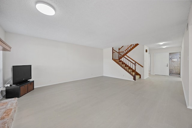 11512 Tin Cup Dr Unit 211, Austin, TX 78750 - unfurnished living room featuring light wood finished floors, stairs, baseboards, and a textured ceiling