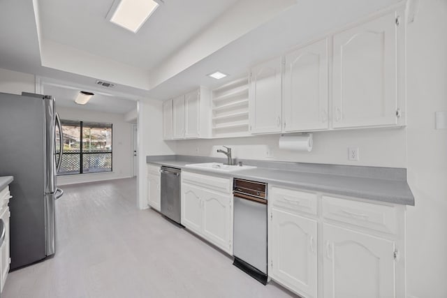 11512 Tin Cup Dr Unit 211, Austin, TX 78750 - kitchen featuring stainless steel appliances, white cabinets, light wood-type flooring, a tray ceiling, and light countertops