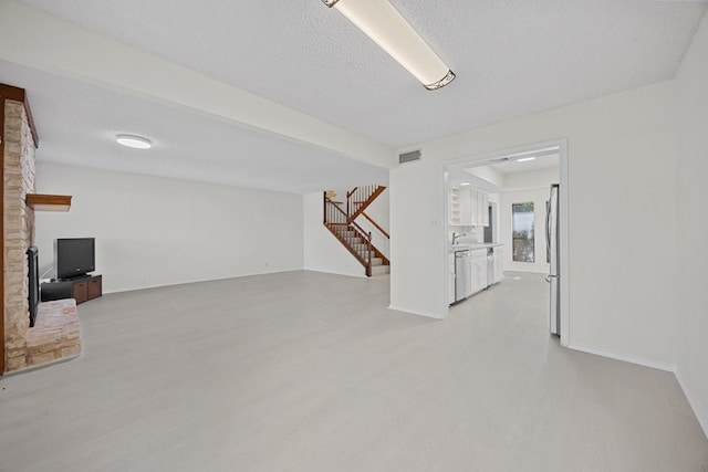 11512 Tin Cup Dr Unit 211, Austin, TX 78750 - basement featuring stairs, freestanding refrigerator, light wood-type flooring, a textured ceiling, and baseboards