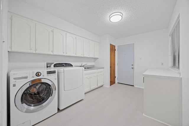 11512 Tin Cup Dr Unit 211, Austin, TX 78750 - laundry area featuring separate washer and dryer, a textured ceiling, cabinet space, and light wood-style floors