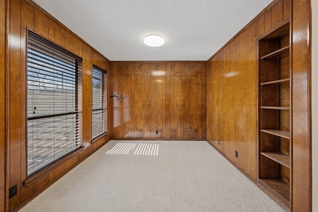 11512 Tin Cup Dr Unit 211, Austin, TX 78750 - carpeted spare room featuring wooden walls, built in shelves, and a textured ceiling