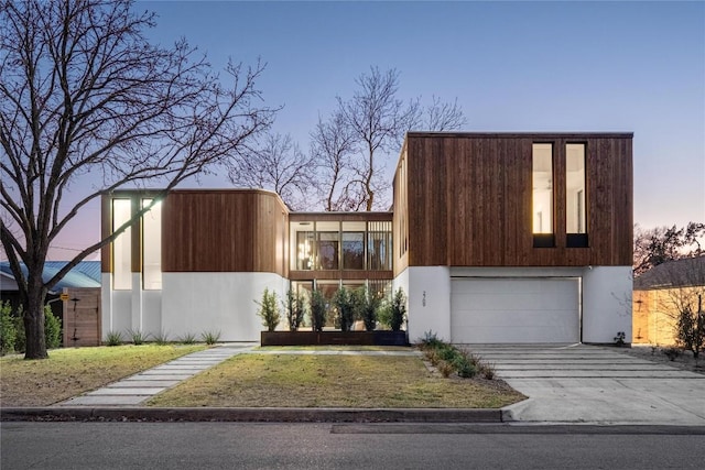 contemporary home with a garage, driveway, and stucco siding