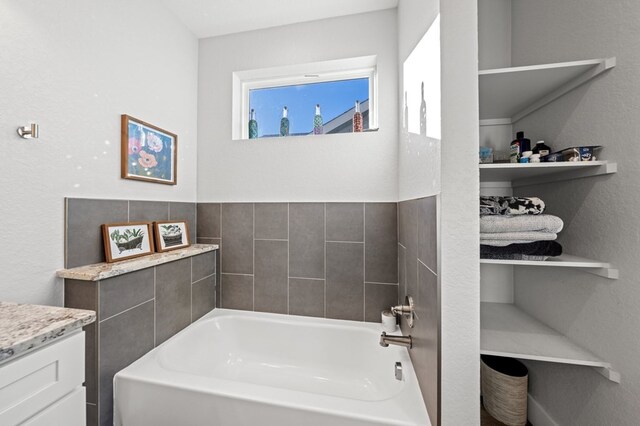 full bathroom featuring a garden tub and vanity