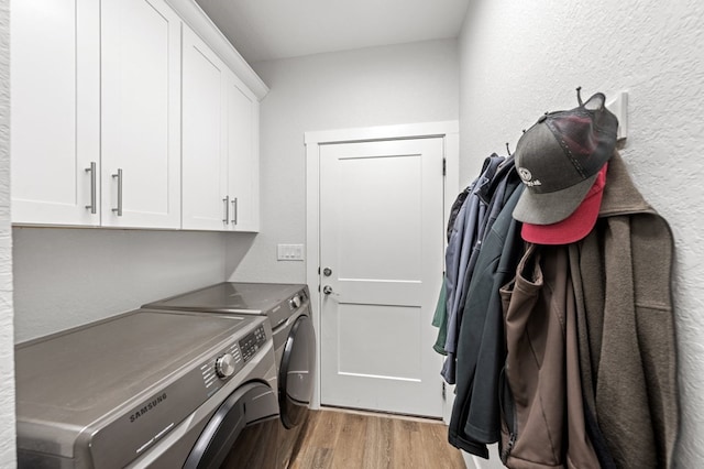 laundry room with light wood-type flooring, washing machine and dryer, and cabinet space