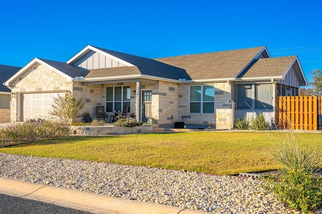 view of front facade with a garage, stone siding, fence, board and batten siding, and a front yard