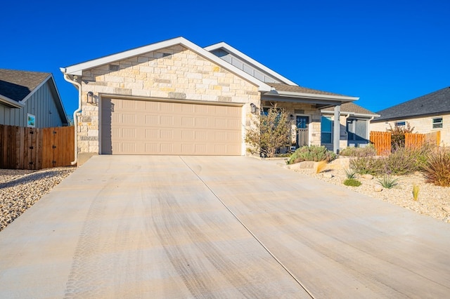 single story home with stone siding, concrete driveway, fence, and an attached garage