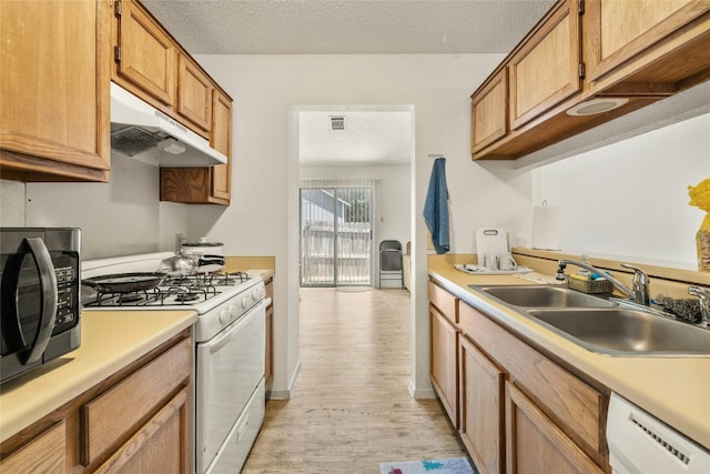 kitchen with light countertops, a sink, dishwasher, under cabinet range hood, and white gas range oven