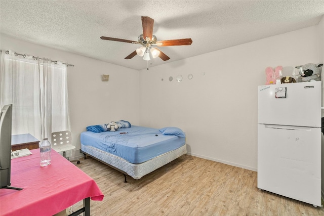 bedroom featuring a textured ceiling, a ceiling fan, baseboards, light wood-type flooring, and freestanding refrigerator