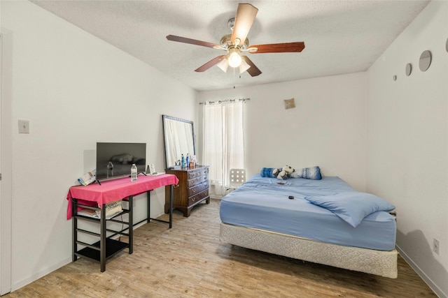 bedroom with a textured ceiling and light wood finished floors