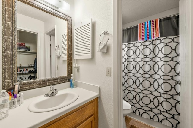 full bathroom with a textured wall, toilet, vanity, a textured ceiling, and a shower with curtain