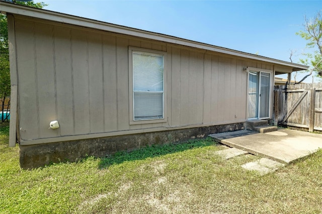 view of side of property with a patio area, fence, and a lawn