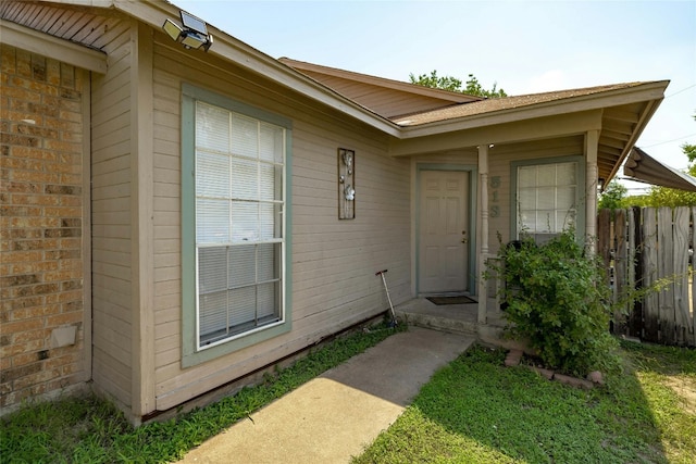 entrance to property with brick siding and fence