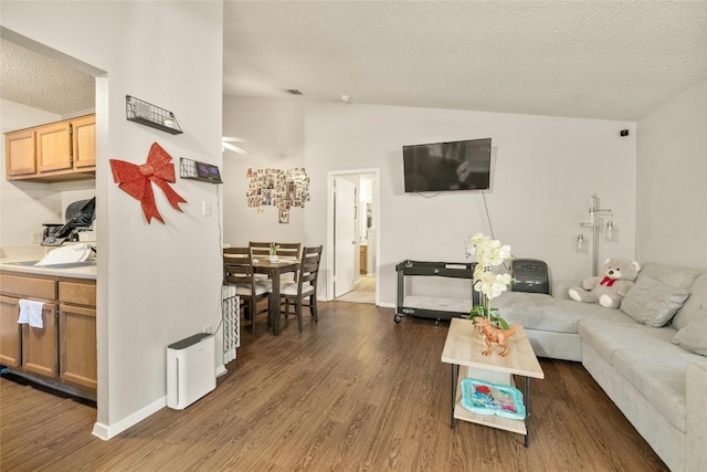 living area with vaulted ceiling, a textured ceiling, dark wood-style floors, and visible vents