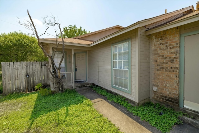 doorway to property with brick siding and fence