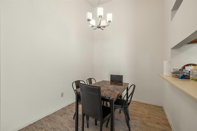 dining space with baseboards, wood finished floors, and a notable chandelier