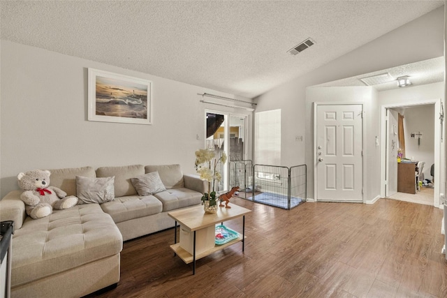 living area featuring lofted ceiling, a textured ceiling, visible vents, and wood finished floors