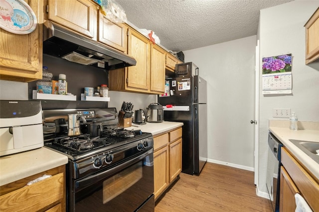 kitchen with light countertops, a textured ceiling, light wood-type flooring, under cabinet range hood, and black appliances