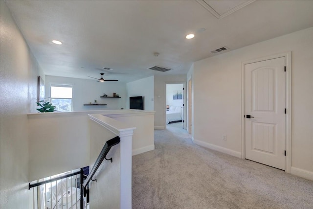 hallway with light colored carpet, baseboards, visible vents, and an upstairs landing