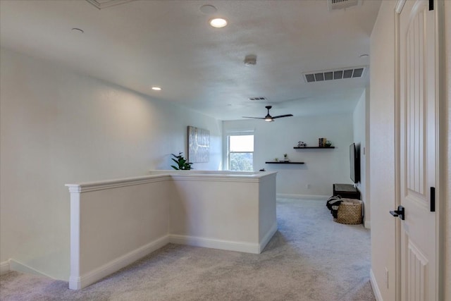 hall featuring baseboards, an upstairs landing, visible vents, and light colored carpet