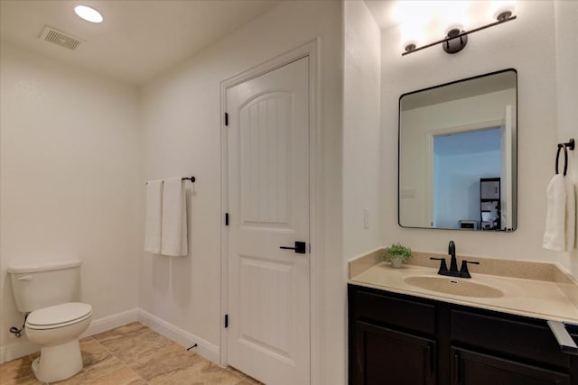 bathroom with baseboards, visible vents, vanity, and toilet