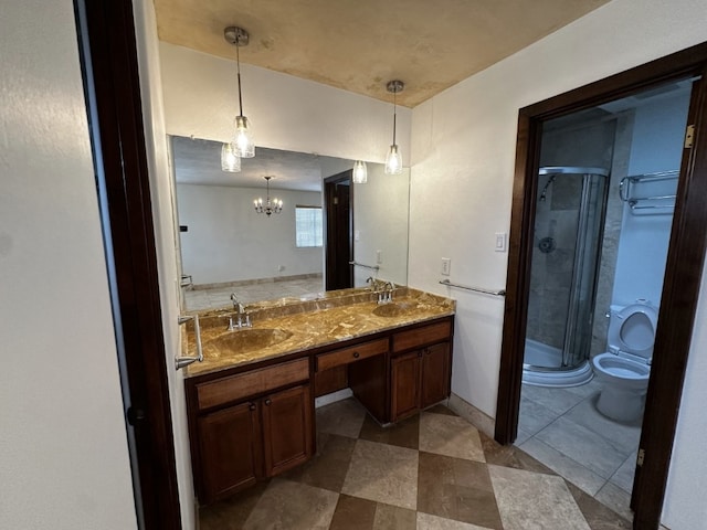 bathroom with a chandelier, a stall shower, a sink, and double vanity