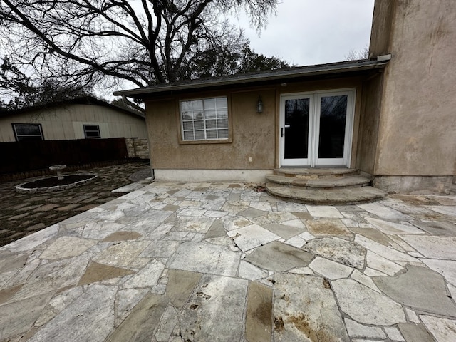 rear view of house with entry steps, stucco siding, and a patio