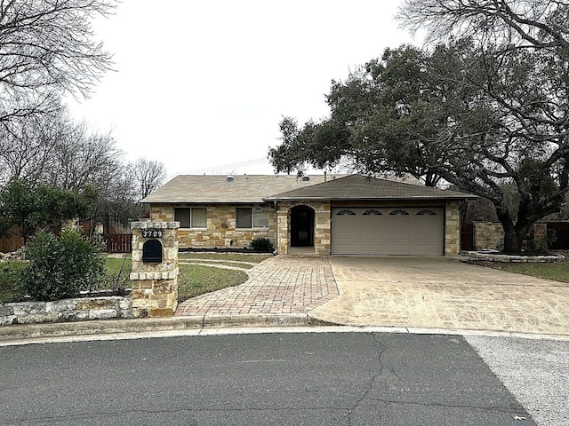 ranch-style home with driveway, stone siding, a garage, and fence