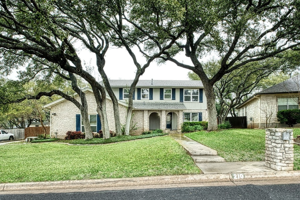 view of front of house featuring roof with shingles, a front yard, and fence