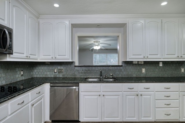 kitchen with stainless steel appliances, white cabinets, a sink, and dark stone countertops