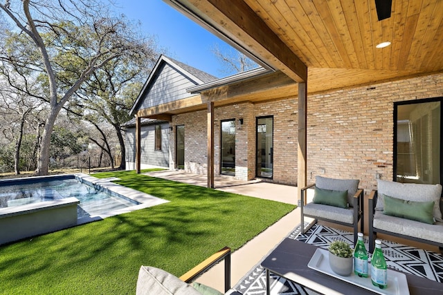 exterior space with a patio area, a yard, an outdoor pool, and brick siding