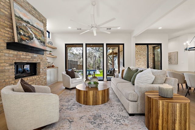 living room featuring ceiling fan with notable chandelier, a fireplace, light wood-style flooring, and recessed lighting