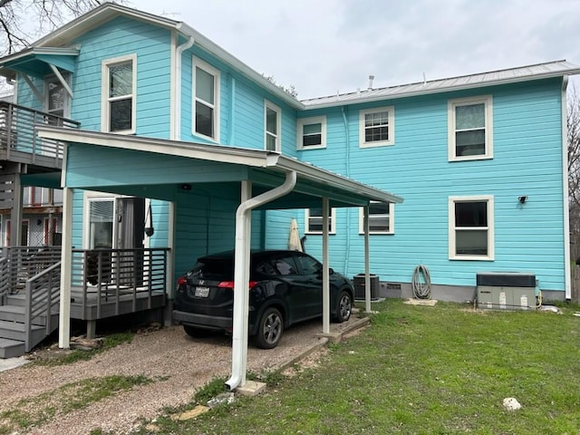 view of front of home with a carport, central AC unit, crawl space, and a front yard