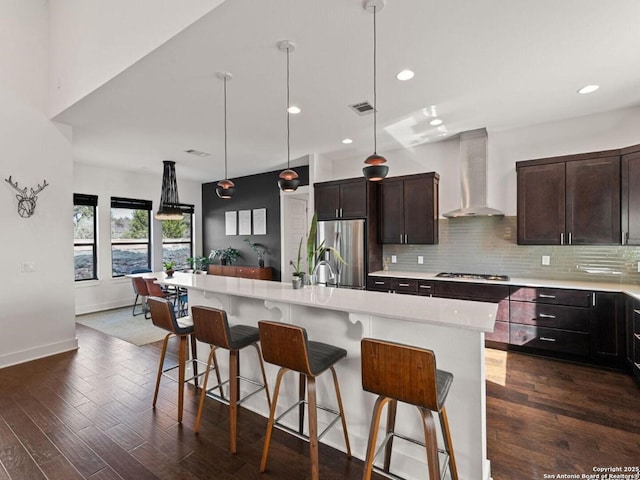 5922 Keller Rdg, New Braunfels, TX 78132 - kitchen featuring wall chimney range hood, a breakfast bar, light countertops, stainless steel refrigerator, and dark wood-type flooring
