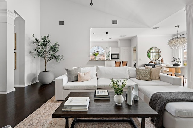 living area featuring visible vents, vaulted ceiling, and wood finished floors