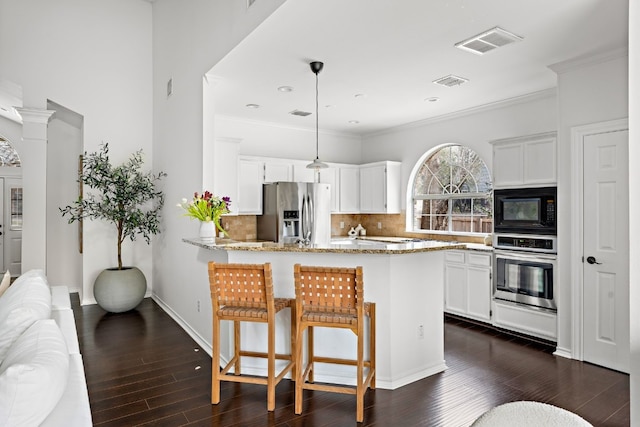 kitchen with stainless steel appliances, light stone counters, a peninsula, and white cabinets