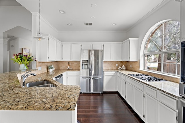 kitchen featuring visible vents, a peninsula, stainless steel appliances, pendant lighting, and a sink