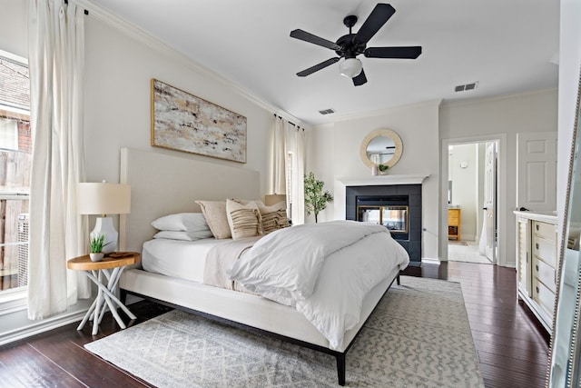 bedroom with dark wood-style floors, visible vents, crown molding, and a tile fireplace