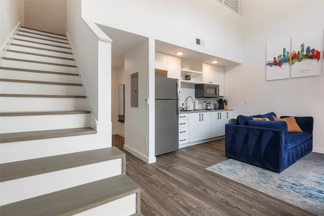 interior space with a towering ceiling, baseboards, visible vents, and wood finished floors