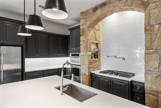 kitchen with stainless steel appliances, light countertops, a sink, and dark cabinetry