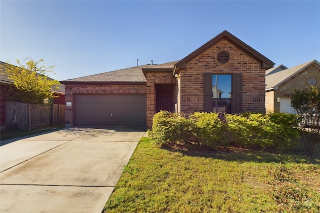 view of front of property with brick siding, an attached garage, fence, driveway, and a front lawn