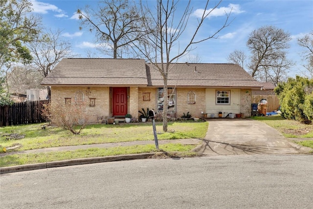 ranch-style house featuring entry steps, a shingled roof, brick siding, fence, and a front lawn