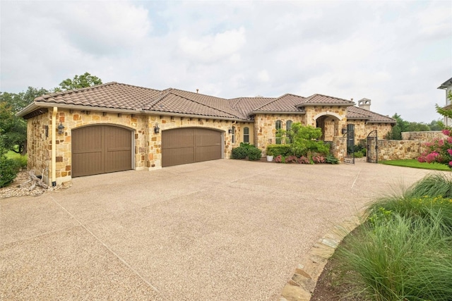 mediterranean / spanish-style house featuring a garage, stone siding, a tile roof, and driveway