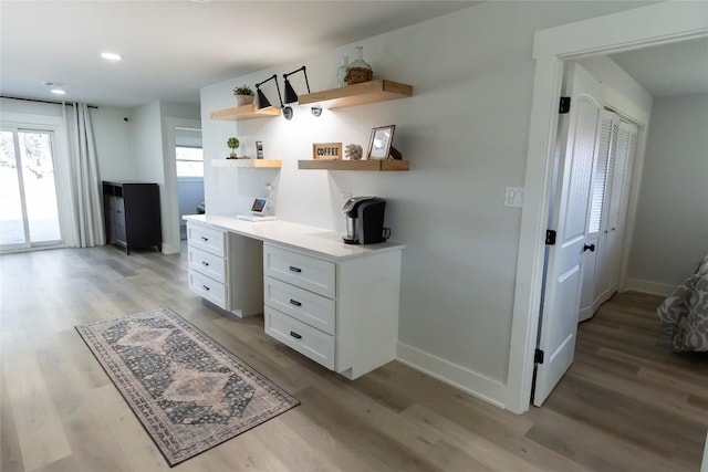 office featuring light wood-type flooring, baseboards, built in desk, and recessed lighting