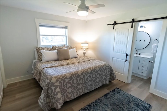 bedroom featuring a barn door, baseboards, ceiling fan, and wood finished floors