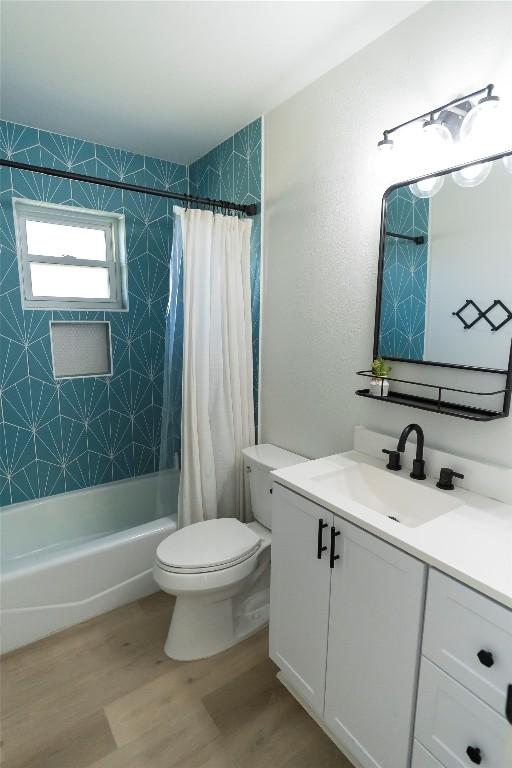 full bathroom with toilet, shower / bathtub combination with curtain, wood finished floors, and vanity